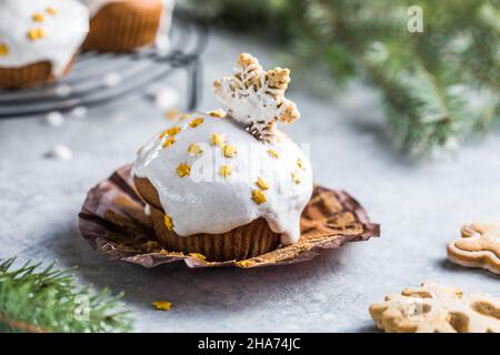 Cupcake di Natale. Dessert di Natale con gocce di cioccolato e marshmallow. Sfondo in legno con decorazioni natalizie e rami di abete. Foto Stock