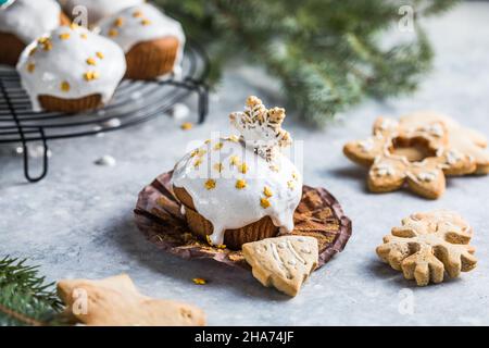 Cupcake di Natale. Dessert di Natale con gocce di cioccolato e marshmallow. Sfondo in legno con decorazioni natalizie e rami di abete. Foto Stock