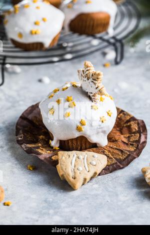 Cupcake di Natale. Dessert di Natale con gocce di cioccolato e marshmallow. Sfondo in legno con decorazioni natalizie e rami di abete. Foto Stock