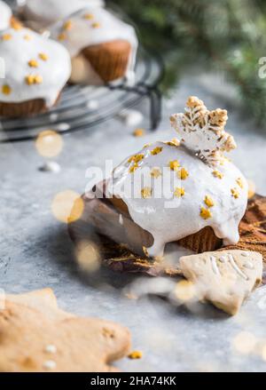 Cupcake di Natale. Dessert di Natale con gocce di cioccolato e marshmallow. Sfondo in legno con decorazioni natalizie e rami di abete. Foto Stock