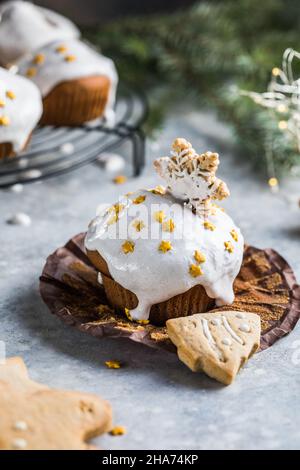 Cupcake di Natale. Dessert di Natale con gocce di cioccolato e marshmallow. Sfondo in legno con decorazioni natalizie e rami di abete. Foto Stock