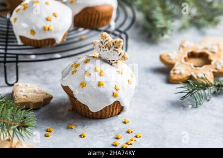 Cupcake di Natale. Dessert di Natale con gocce di cioccolato e marshmallow. Sfondo in legno con decorazioni natalizie e rami di abete. Foto Stock