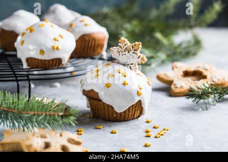 Cupcake di Natale. Dessert di Natale con gocce di cioccolato e marshmallow. Sfondo in legno con decorazioni natalizie e rami di abete. Foto Stock