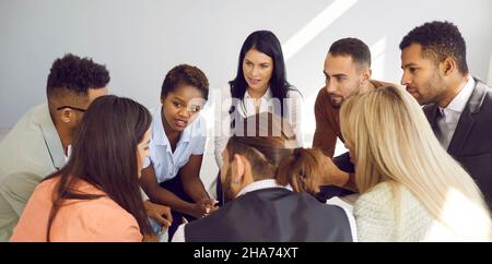 Gruppo di persone multirazziali che hanno una conversazione e l'ascolto di una giovane donna Foto Stock