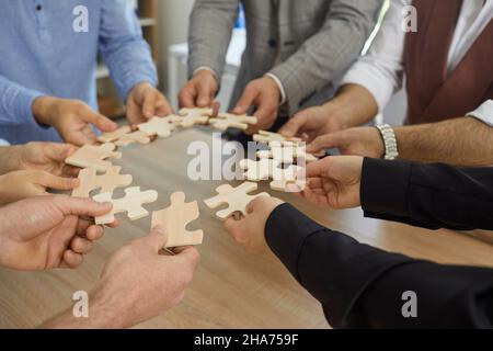 Le mani di uomini d'affari, vestiti con magliette casual, tengono un puzzle di carta Foto Stock