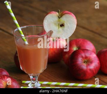 Succo di mela fresco in vetro con mela rossa su tavola rustica di legno. Fuoco selettivo, Foto Stock