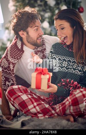 Primo piano di una giovane coppia felice che ha un meraviglioso momento di condividere regali di natale in un'atmosfera festosa a casa. Natale, casa, relationsh Foto Stock