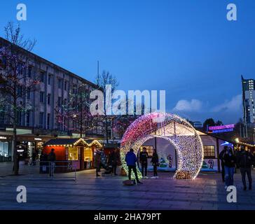 Le luci di Natale aggiungono calore alle piccole bancarelle di legno del mercatino di Natale di Plymouth, dove un'arcata coulruful fornisce un posto perfetto per il souven Foto Stock