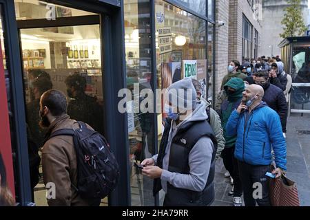 Le persone si accaparrano al di fuori del Rough Trade a Bristol, dove viene venduta una T-shirt disegnata dall'artista di strada Banksy per sostenere quattro persone accusate di danni criminali in relazione alla rovesciamento di una statua del commerciante di schiavi Edward Colston. Data foto: Sabato 11 dicembre 2021. Foto Stock