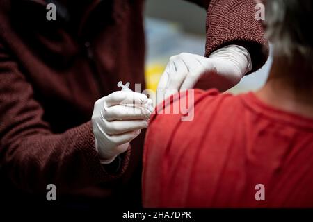 11 dicembre 2021, Brandeburgo, Henningsdorf: Un medico vaccina un uomo contro il coronavirus durante la campagna di vaccinazione del distretto di Oberhavel presso la scuola elementare del nord di Hennigsdorf. Due squadre mobili di vaccinazione offrono la prima, la seconda e la terza vaccinazione senza appuntamenti. Foto: Fabian Sommer/dpa Foto Stock