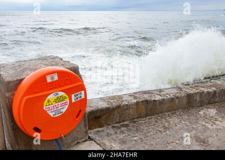 Anello di salvataggio di boa di vita di fronte a onde e mare accidentato in Scarborough Yorkshire Foto Stock