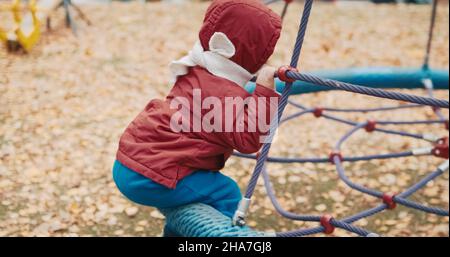 Piccolo, carino bambino corre su un swing nel cortile su una passeggiata Foto Stock