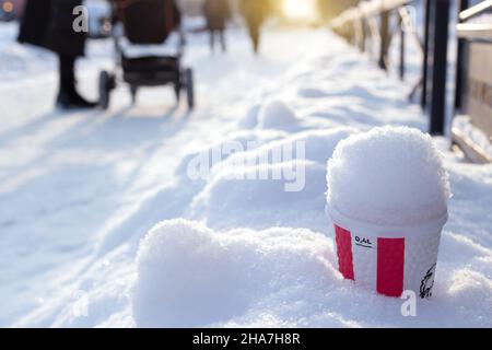 Punch caldo in una tazza di carta marca KFS in una nevicata sulla strada invernale Foto Stock