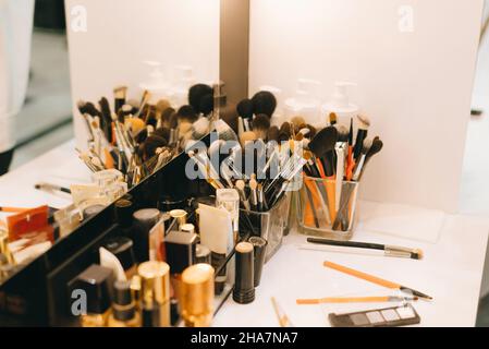 Foto di molti accessori per il trucco vicino al tavolo e specchio. Foto Stock