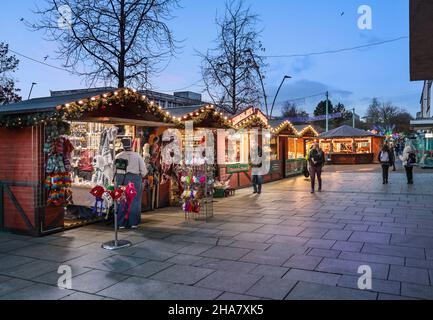 Le luci di Natale aggiungono un calore alle piccole bancarelle di legno del mercatino di Natale di Plymouth Foto Stock