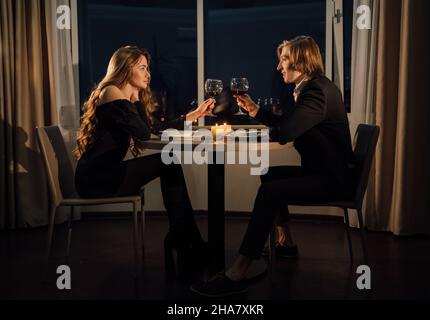 Cena di San Valentino, coppia innamorata a casa bere vino in bicchieri, cena romantica per due, abbiamo il concetto di toast Foto Stock