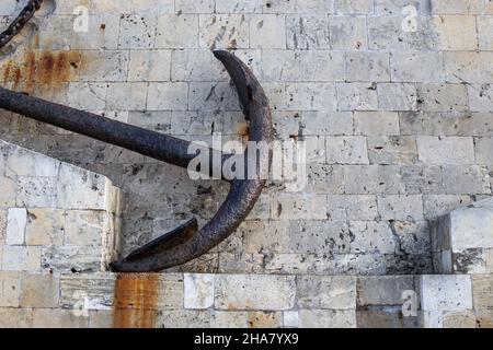 arrugginita vecchia ancora di ferro si trova sulle ciottoli del lungomare Foto Stock