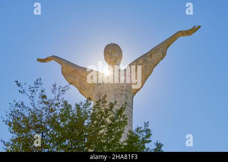 La statua di Cristo Redentore a Maratea in raggi di sole contro un cielo blu, Basilicata, Italia. Il Salvatore abbraccia la terra con le sue mani, concep religioso Foto Stock