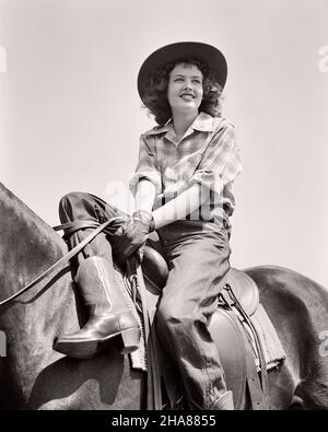 1940S RAGAZZA ADOLESCENTE CHE INDOSSA ABITI BEST WESTERN STIVALI COWBOY CAMICIA A QUADRI E CAPPELLO IN RELAXD POSA SEDUTO A CAVALLO CON BEST WESTERN SELLA - H1589 HAR001 HARS 1 GIOVANI STILE CAVALLI EQUILIBRIO VACANZA COTONE FELICE GIOIA LIFESTYLE SODDISFAZIONE FEMMINE RURALE VITA DOMESTICA SPAZIO COPIA MEZZA LUNGHEZZA SIGNORE PERSONE SELLA ADOLESCENTE RAGAZZA BEST WESTERN FIDUCIA DENIM TRASPORTO B&W TEMPO LIBERO PILOTA SOGNI CAVALLO FELICITÀ MAMMIFERI ALLEGRO AVVENTURA VIAGGIO DI PIACERE E FUGA LOW ANGLE RICREAZIONE RELAXD COWGIRL VACANZE SORRISI DUDE RANCH GIOIOSO TEENAGED JEANS BLU INFORMALE GIOVANI MAMMIFERO POSA TWILL VACANZE Foto Stock