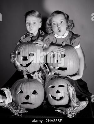 1950S RAGAZZO E RAGAZZA IN PIEDI SOPRA QUATTRO JACK-O-LANTERNE HALLOWEEN SCOLPITO ZUCCHE CON PAURA ESPRESSIONI FACCIALI SPAVENTATE - H2928 DEB001 HARS LIFESTYLE SPOOKY CELEBRATION FEMMINE FRATELLI STUDIO SHOT HOME VITA COPIA SPAZIO PERSONE MASCHI PAURA SIMBOLI SPAVENTATI FRATELLI SORELLE ESPRESSIONI B&W OCCHIO CONTATTO ANSIA TESTA E SPALLE ANSIOSO ZUCCHE ED ECCITAZIONE AUTUNNO STAGIONE SCOLPITO FRATELLO CONCETTO CONNESSIONE CONCETTUALE MINACCIATO PAURA IMMAGINAZIONE UNEASY DEB001 JACK-O-LANTERNE OTTOBRE CONCETTI SIMBOLICI GIOVANI OTTOBRE 31 ETNIA AUTUNNALE BIANCA E NERA ETNIA CAUCASICA Foto Stock