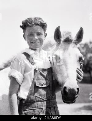 1930S RITRATTO DI SORRIDENTE FRECKLE-FACCIA RICCI CAPELLI RAGAZZO FATTORIA INDOSSARE TUTE CON IL BRACCIO INTORNO AL CAVALLO GUARDANDO LA MACCHINA FOTOGRAFICA - H4148 HAR001 HARS VECCHIA MODA 1 GIOVANE CUTE STILE FACCIALE CAVALLI EQUILIBRIO LAVORO DI SQUADRA ABBRACCIARE FELICE GIOIA LIFESTYLE SODDISFAZIONE CELEBRAZIONE WINNING RURALE HEALTHINESS HOME VITA COPIA SPAZIO MEZZA LUNGHEZZA ABBRACCIO ISPIRAZIONE TUTE CURA AGRICOLTURA MASCHI ADOLESCENZA RAGAZZO SPIRITUALITÀ FIDUCIA ABBRACCIARE LE ESPRESSIONI AGRICOLTURA B&W OCCHIO CONTATTO SOGNI FELICITÀ MAMMIFERI BENESSERE ALLEGRO LA SUA FORZA ECCITAZIONE AGRICOLTORI CURLY ORGOGLIO CAMICIA BIANCA DI OPPORTUNITÀ SORRISI CONCETTUALE DELLA CONNESSIONE Foto Stock