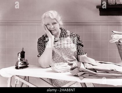 1930S 1940S DONNA ANZIANA STANCA CHE GUARDA LA MACCHINA FOTOGRAFICA APPOGGIATA SULL'ASSE DA STIRO CON FERRO E UN MUCCHIO DI VESTITI APPENA STIRATI CAMICIE - H6701 HAR001 HARS FERRO DEGLI ANZIANI ESPRESSIONE CASALINGA FERRO VECCHIO TEMPO OCCUPATO NOSTALGIA PENDENTE VECCHIO STILE DEL VISO 1 PREOCCUPATEVI STANCO LIFESTYLE CHORES ANZIANE FEMMINE MOODY HOME VITA COPIA SPAZIO MEZZA LUNGHEZZA SIGNORE PERSONE ESPRESSIONI DISTURBATE MEDIO-ETÀ B&W PREOCCUPATO TRISTEZZA OCCHIO CONTATTO LIBERTÀ HOMEMAKER SOGNI VECCHIAIA CASALINGHE DI MEZZA ETÀ DONNA OLDSTERS OLDSTER E CAMICIE LAVORO OCCUPAZIONE CASALINGHE UMORE OCCUPAZIONI ANZIANI IL GLUM CONCETTUALE SFUGGE ALLA RIPETIZIONE STIRATA Foto Stock