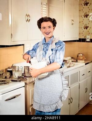 1950S SORRIDENTE BRUNETTA DONNA CASALINGA CHE INDOSSA GREMBIULE IN CUCINA MESCOLANDO UNA CIOTOLA DI PASTELLA GUARDANDO LA MACCHINA FOTOGRAFICA - H962C HAR001 HARS SALUBRITÀ HOME VITA COPIA SPAZIO MEZZA LUNGHEZZA SIGNORE PERSONE CURA FIDUCIA MIX PASTELLA OCCHIO CONTATTO BRUNETTE SUCCESSO HOMEMAKER SOGNI AGITARE FELICITÀ HOMEMAKERS ALLEGRO TEMPO LIBERO FORZA AGITAZIONE SCELTA DI SCELTA DI PROGRESSO RICREAZIONE ORGOGLIO AUTORITÀ CASALINGHE OCCUPAZIONI SORRISI CONCETTUALE GIOIOSO ELEGANTE CREATIVITÀ MEDIO-ADULTO DONNA MEDIO-ADULTO PRECISIONE CAUCASICA ETNIA PREPARAZIONE ALIMENTARE HAR001 VECCHIO STILE Foto Stock