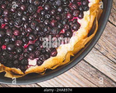 Torta di ribes nero appena sfornata. Vista macro di torta fatta in casa con frutti di bosco estivi su un tavolo di legno. Vista dall'alto. Crostata con frutti di bosco. Pasticceria gourmet Foto Stock