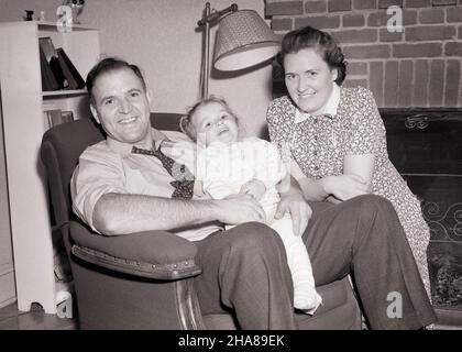 1940S RITRATTO DI FAMIGLIA DAD SEDUTA IN POLTRONA FIGLIA SUL SUO GREMBO MADRE SI INGINOCCHIA ACCANTO A POGGIARE SU SEDIA BRACCIO GUARDANDO ALLA MACCHINA FOTOGRAFICA - J5733 HAR001 HARS ARM MOM INDOOR NOSTALGICO COPPIA MADRI VECCHIO TEMPO NOSTALGIA PENDENTE VECCHIO MODO 1 GIOVANI COMPIACENTI FAMIGLIE GIOIA LIFESTYLE SODDISFAZIONE DONNE CASE SALUBRITÀ HOME VITA COPIA SPAZIO AMICIZIA MEZZA LUNGHEZZA DONNE FIGLIE PERSONE RESIDENZIALI MASCHI EDIFICI PADHERS B&W LAP EYE CONTATTO FELICITÀ ALLEGRO SUO PAPÀ ORGOGLIO CONTENTMENT CASE SORRISI CONNESSIONE ACCANTO FACILE GIOIOSO RESIDENCE GENTE CRESCITA I GIOVANI SI INGINOCCHIANO NELL'UOMO DI METÀ ADULTO Foto Stock