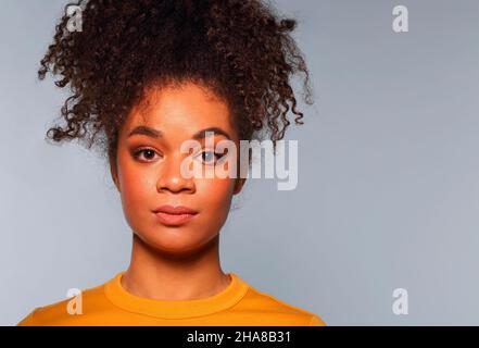 Ritratto di etnia giovane donna di razza africana con focalizzata calma espressione facciale posando su sfondo grigio studio, seria focalizzata afro femmina con Foto Stock