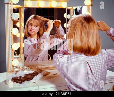 1960S RAGAZZA TEEN SEDUTA DI FRONTE ALLO SPECCHIO DI TRUCCO CON LUCI CHE METTONO I RULLI NEI SUOI CAPELLI - KJ3344 HAR001 HARS RULLI GROOMING TESTA E SPALLE ESECUTORE AUBURN INTRATTENITORE ATTORI ADOLESCENTI DI FRONTE A ANIMATORI GIOVANI ARTISTI INTERPRETI ETNIA CAUCASICA HAR001 VECCHIO STILE Foto Stock