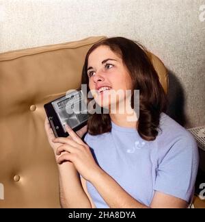 1950S 1960S BRUNETTE ADOLESCENTE DONNA CHE ASCOLTA MUSICA SU TRANSISTOR RADIO - R21091C HAR001 HARS USA COPY SPACE PERSONE ADOLESCENTI DI MEZZA LUNGHEZZA ISPIRAZIONE STATI UNITI D'AMERICA ADOLESCENZA RAGAZZA INTRATTENIMENTO PORTATILE BRUNETTE SOGNI FELICITÀ ALLEGRO TRASMISSIONE IN RETE TRANSISTOR SORRISI CONNESSIONE JOYFUL TEENAGED MUSICA POPOLARE ROCK E ROLL FUNZIONAMENTO A BATTERIA COMUNICARE COMUNICAZIONI GIOVANI ADOLESCENTI IDOLI CAUCASICI ETNIA PALMARE HAR001 VECCHIO ALLA MODA Foto Stock