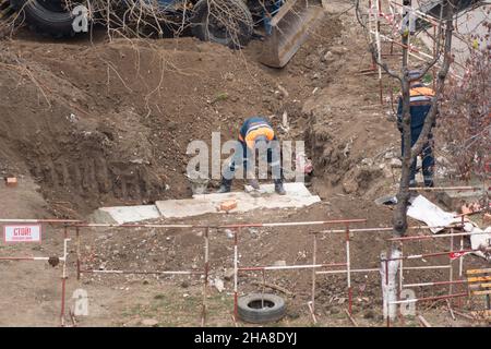 Tiraspol, Repubblica non riconosciuta di Transnistria - 18 novembre 2021 Un gruppo di lavoratori svolge lavori di riparazione su una rete di riscaldamento in un'area residenziale Foto Stock