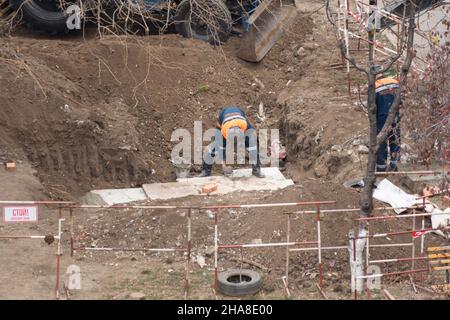 Tiraspol, Repubblica non riconosciuta di Transnistria - 18 novembre 2021 Un gruppo di lavoratori svolge lavori di riparazione su una rete di riscaldamento in un'area residenziale Foto Stock