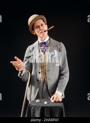 1910S 1920S PERSONAGGIO CON MAN BARKER BOWLER CAPPELLO CIGAR CANE SHELL GIOCO SUL TAVOLO GUARDANDO LA MACCHINA FOTOGRAFICA - S5264C HAR001 HARS PERSONAGGIO FANTASIA MASCHI RISCHIO CARNEVALE FIDUCIA GIUBBOTTO MEDIO-ETÀ UOMO DI MEDIO-ETÀ OCCHIO CONTATTO OBIETTIVI GIOCO FELICITÀ OPERATORE OMBRA CHEAT CRAVAT CON CON MAN CROOK SCOUNDREL SHYSTER CONTROLLATO CARNIE CARNY CONCHIGLIE FIDUCIA GIOCO TRUFFA VELOCE NOCE OCCUPAZIONI ACUTE SORRISI PEA TRUFFA SWINDLER EVASIVE FACILE GIOIOSA SHELL GIOCO ELEGANTE DIPENDENTE TRUFFA BARKER DERBY HAT MID-ADULT UOMO DI VENDITA SIDESHOW TRICKSTER INAFFIDABILE CAUCASICO POSSIBILITÀ DI ETNIA CHE DIMOSTRA DEVIOSISMO HAR001 Foto Stock