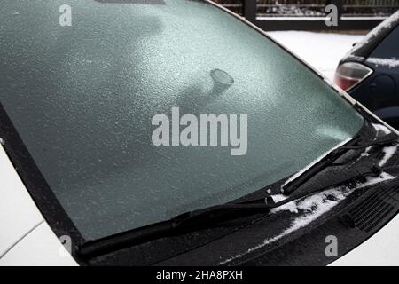 Strato di pioggia di ghiaccio che copre la finestra di vetro dell'automobile nella fredda giornata di inverno all'aperto. Concetto di condizioni meteorologiche estreme. Foto Stock