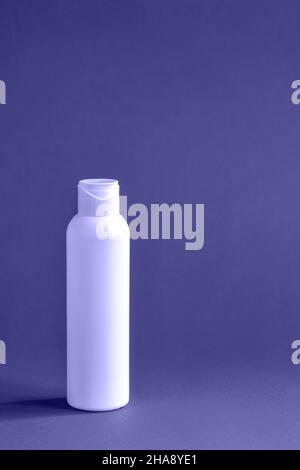 Bottiglia in plastica bianca con lozione cosmetica su sfondo viola. Igiene, bellezza e cura della pelle del corpo. Spazio di copia. Tonalità molto Peri col Foto Stock