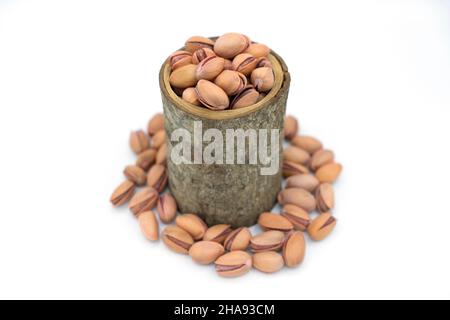 Noci, antep pistacchio, pistacchio in una ciotola di legno naturale versato intorno bianco bacround closeup anteriore Foto Stock