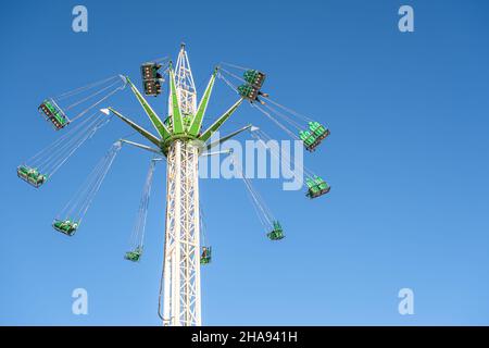 Carosello volante in azione con posti a sedere vuoti in un parco divertimenti Foto Stock