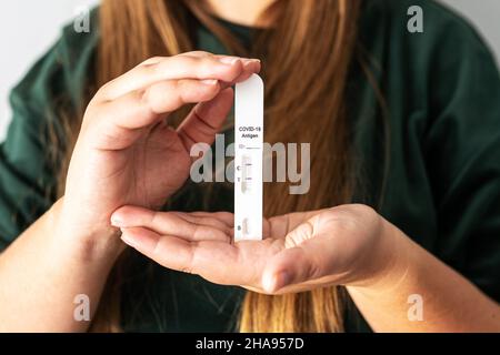 Risultato positivo del test COVID-19 dell'antigene rapido in mani di persone non riconoscibili. La donna contiene una scheda kit Quick coronavirus Antigen Rapid Test. Testato positivo per COVID-19 Concept. Foto Stock