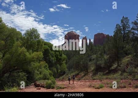 Due escursionisti sul Cathedral Rock Trail vicino a Sedona, Arizona. Cathedral Rock in lontananza è un pinnacolo naturale o da arenaria rossa. Foto Stock