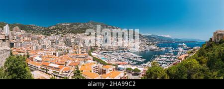 Il Principato di Monaco e Monte Carlo cityscape. Immobiliare di Architettura in montagna collina sullo sfondo. Molti edifici ad alta nell area del centro cittadino. Yacht ormeggiati in città Foto Stock