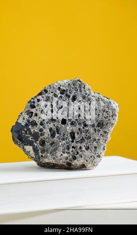 Roccia meteorite su libro di testo, con sfondo marrone chiaro. Foto Stock