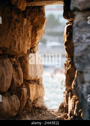 Vista sfocata attraverso la finestra nella vecchia fortezza di pietra nella città vecchia di Budva, Montenegro. Concetto di architettura. Messa a fuoco soft Foto Stock