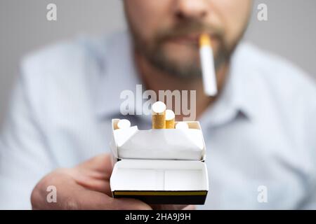 Uomo dare di sigaretta di tabacco in una confezione. Offerta nicotine Smoking concetto. Primo piano fuoco selettivo. Foto Stock