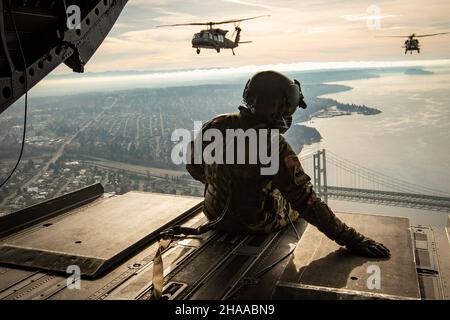 I soldati dell'esercito degli Stati Uniti, assegnati al 96esimo comando della truppa dell'aviazione, la Guardia Nazionale dell'esercito di Washington, viaggiano a Lumen Field per un volo multi-nave delle cerimonie di premame, vicino Seattle, Washington, 21 novembre 2021. La multi-nave, composta da un CH-47 Chinook e due elicotteri UH-60 Black Hawk, è arrivata poco prima della partita di football dei Seattle Seahawks contro gli Arizona Cardinals. (STATI UNITI Guardia Nazionale dell'esercito foto di Sgt. Adeline Witherspoon) Foto Stock