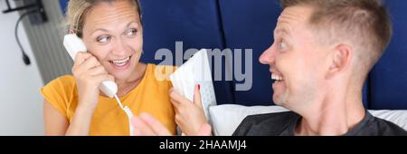 Uomo e donna sdraiati a letto e che parlano al telefono Foto Stock