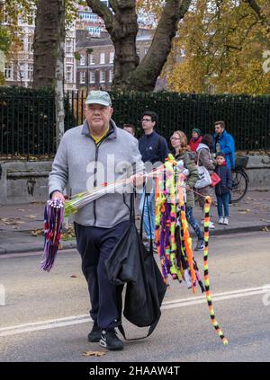 Un uomo cammina lungo Victoria Embankment vendendo oggetti colorati prima del Lord Mayor’s Show, 2021. Foto Stock