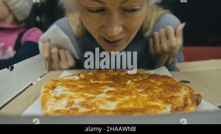 Ragazza mangiare pizza formaggio quattro. Primo piano di giovane donna bocca mangiando golosamente pizza e masticare in ristorante all'aperto. Cibo spazzatura. Pizza da open box. Foto Stock