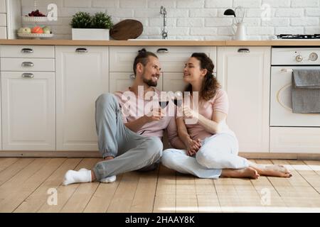 Allegro dolce giovane coppia di canti seduta sul pavimento in cucina Foto Stock